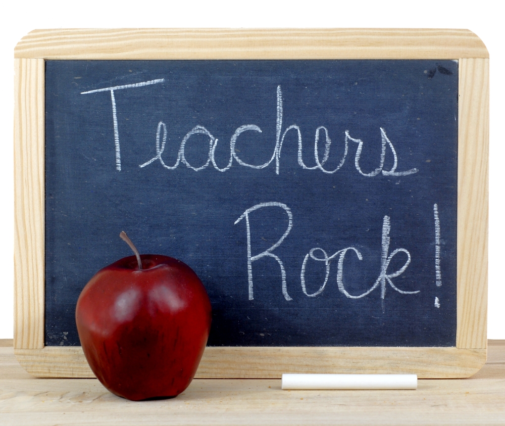 Blackboard that reads “Teachers rock!” next to an apple
