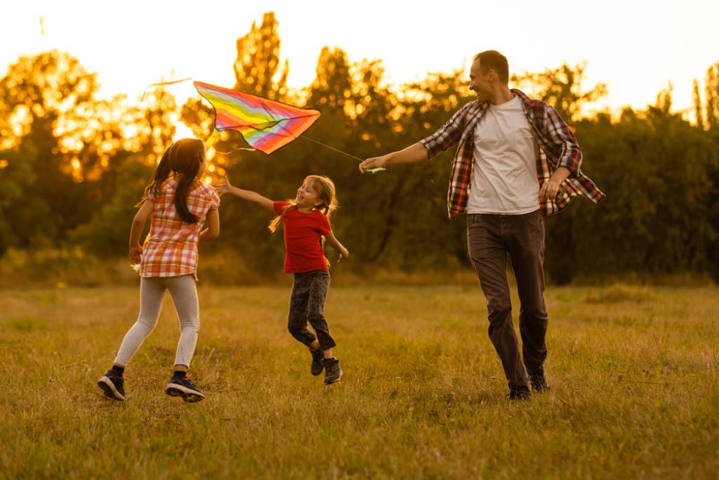 A father flying a kite with his two daughters